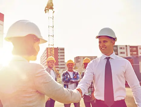 Client and general contractor shaking hands on a construction site
